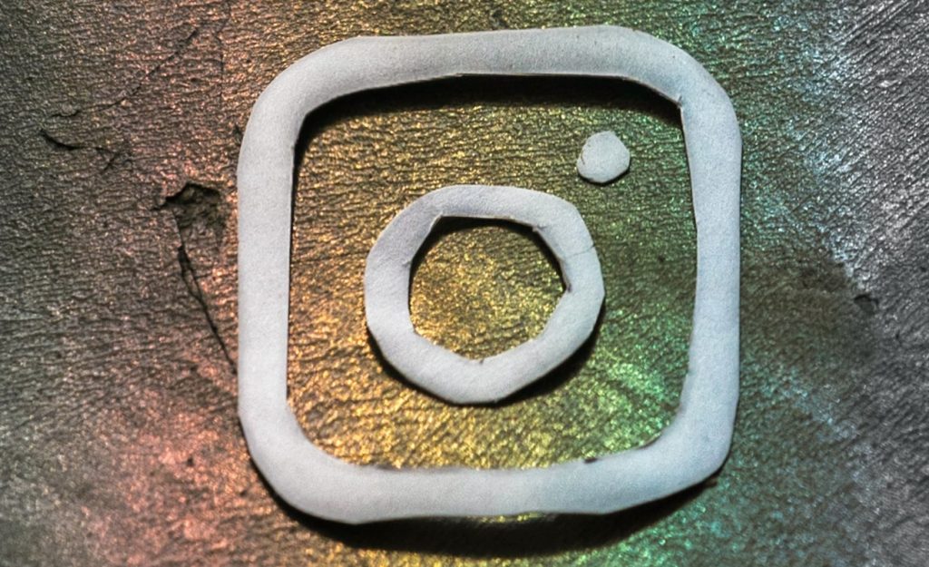 Instagram logo in white with shiny rainbow background