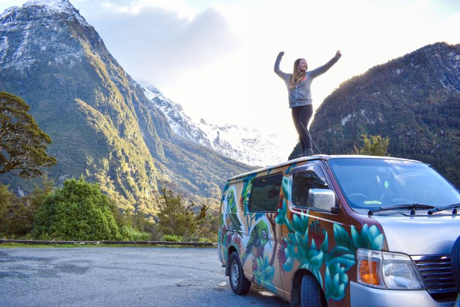 Travel blogger standing on top of a campervan in new zealand - how to make money from your travel blog